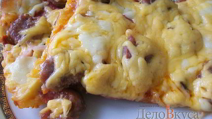 Пицца с домашними колбасками, салями, беконом, моцареллой, твердым сыром и зеленью на тонкой основе